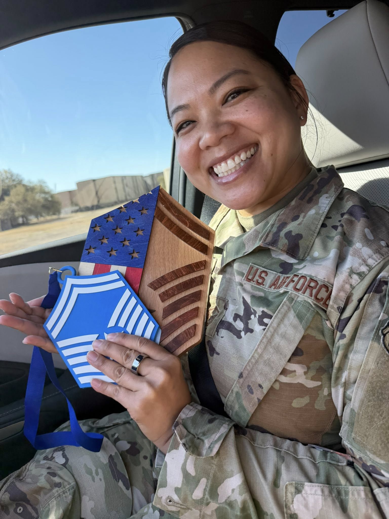 SMSgt Brenda Khamthongath in uniform smiling, holding her new E-8 Senior Master Sergeant chevron.