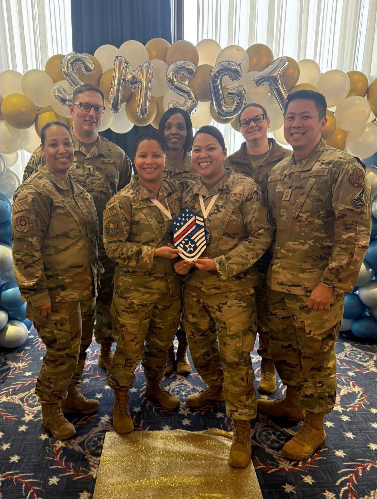 Brenda with team in front of SMSGT gold and white balloons.